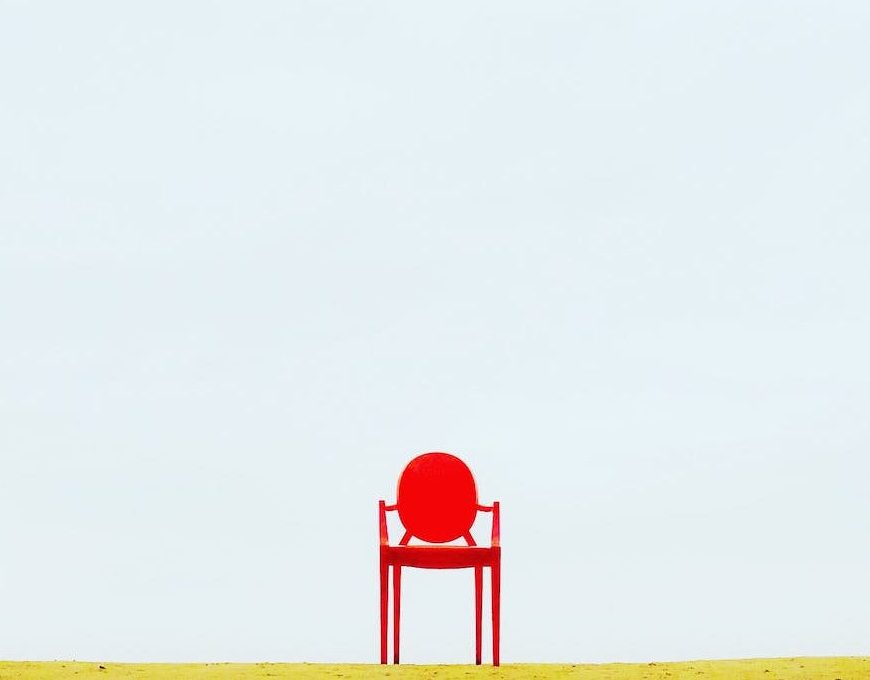 empty red chair on a garden, clear blue sky